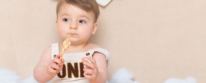 a little boy eating cake in a neutrally styled cake smash photo shoot