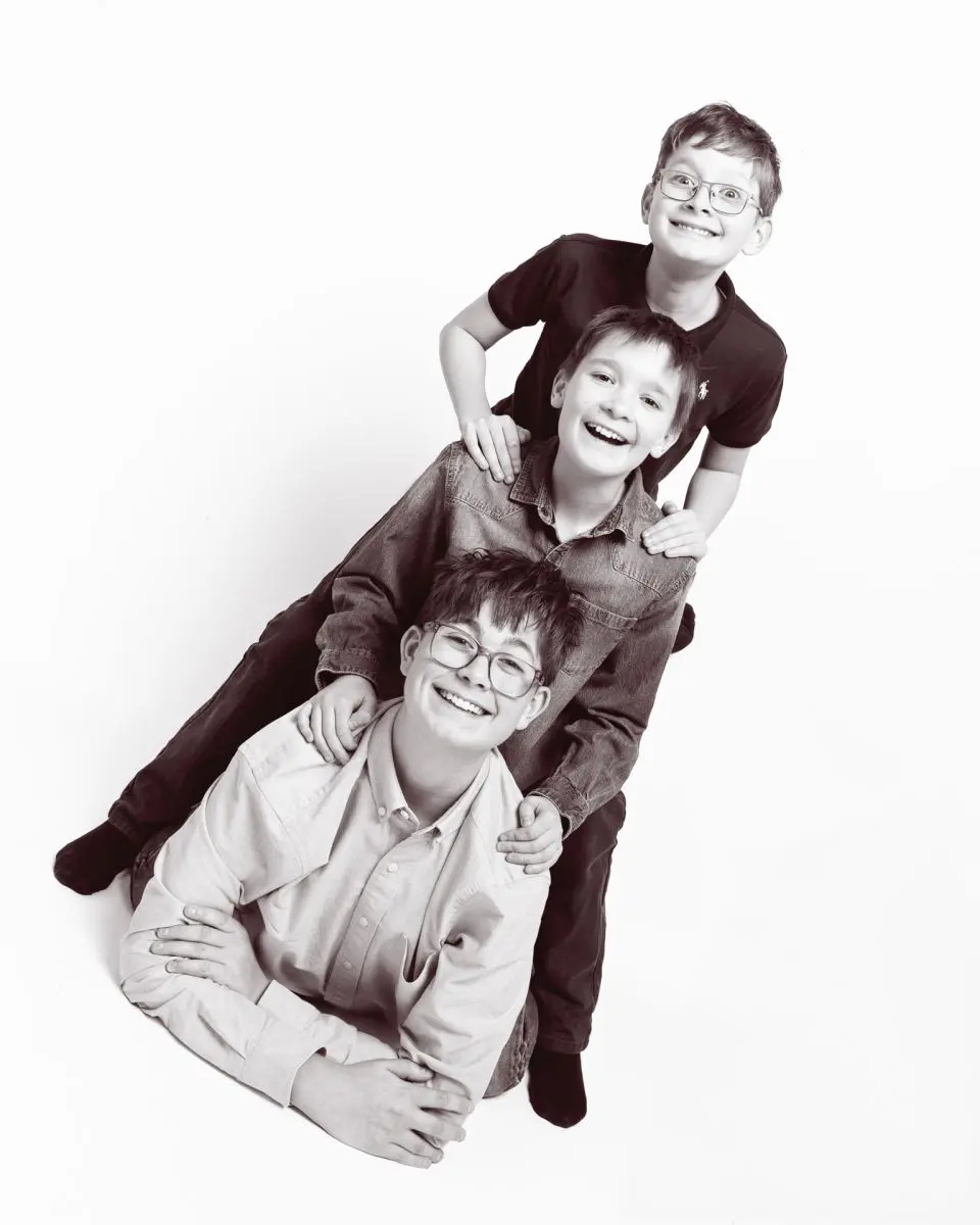 a black and white image of three brothers forming a stack in a portrait studio