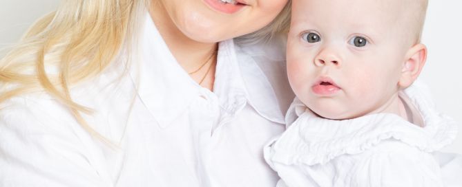 a mother and daughter dressed in white pose cheek to cheek