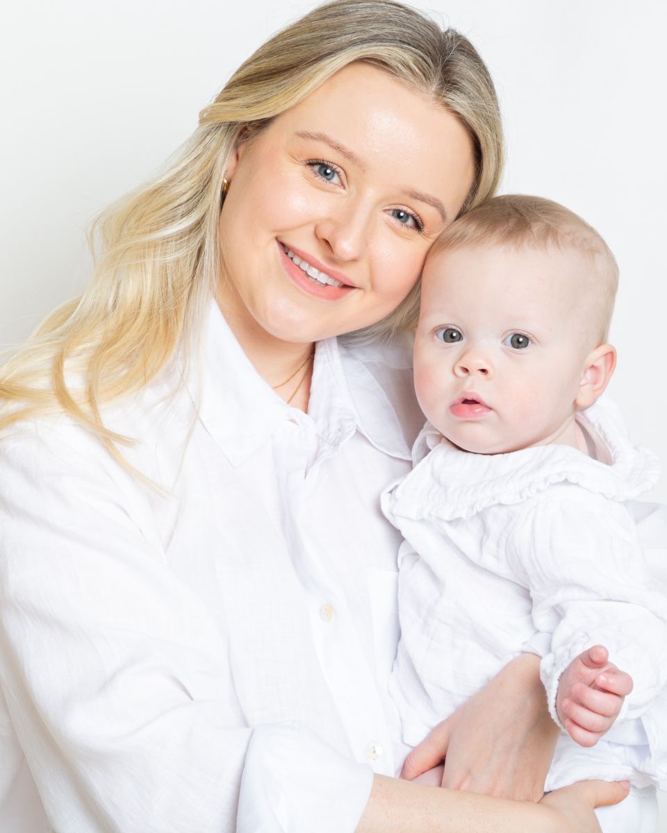 a mother and daughter dressed in white pose cheek to cheek