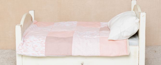 My mini bed styled with a peach handmade patchwork quilt