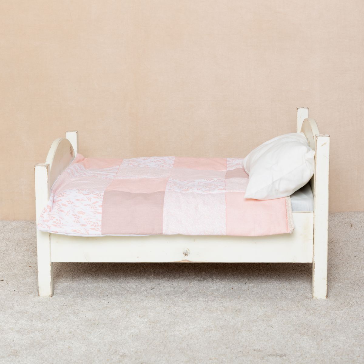 My mini bed styled with a peach handmade patchwork quilt