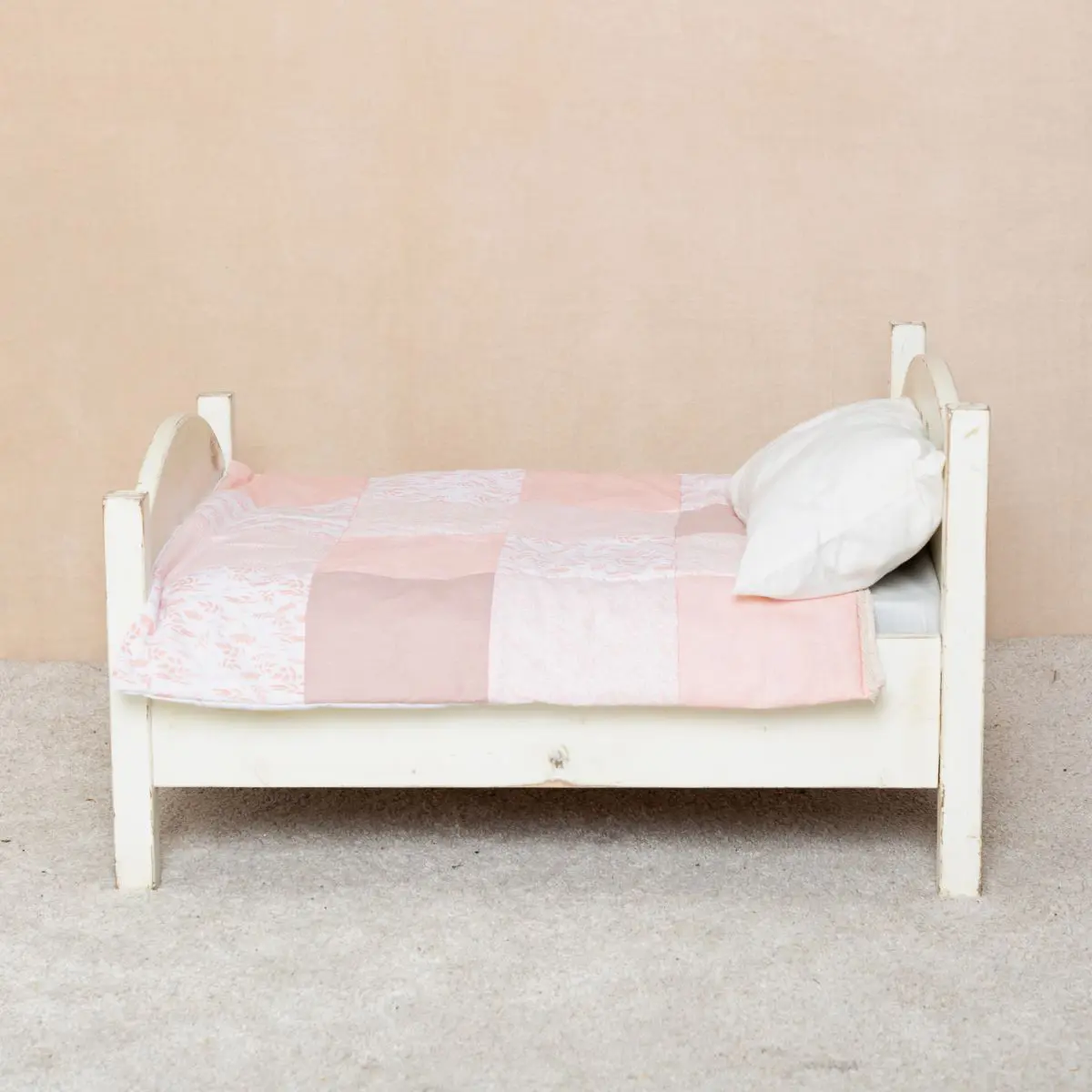 My mini bed styled with a peach handmade patchwork quilt