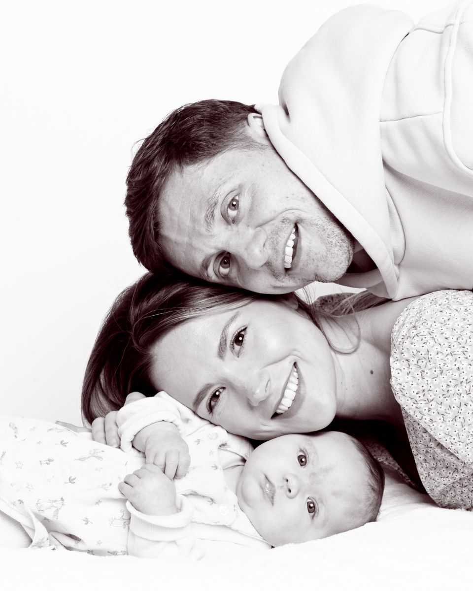 a mum, dad and baby make a stack of their heads at a portrait photo shoot