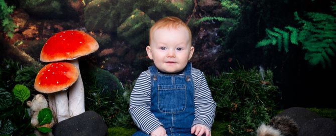 a little boy in dungarees at a woodland themed set photo shoot