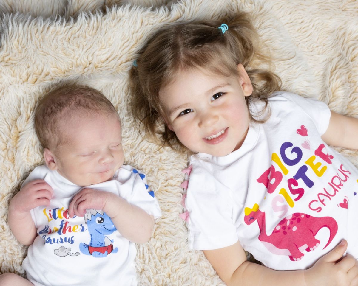 a newborn poses sleeping with his big sister