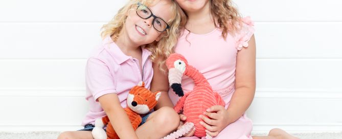 Brother and sister pose together holding toys