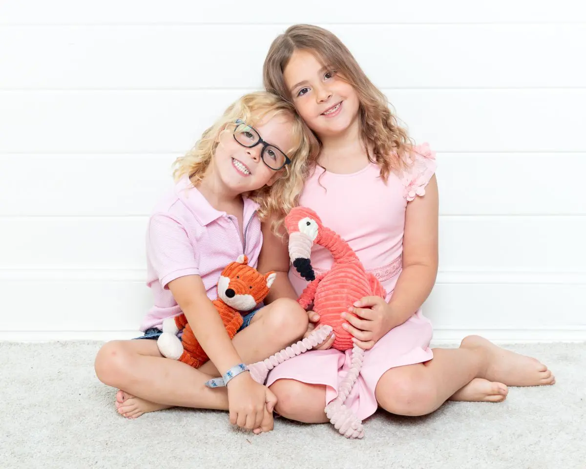 Brother and sister pose together holding toys