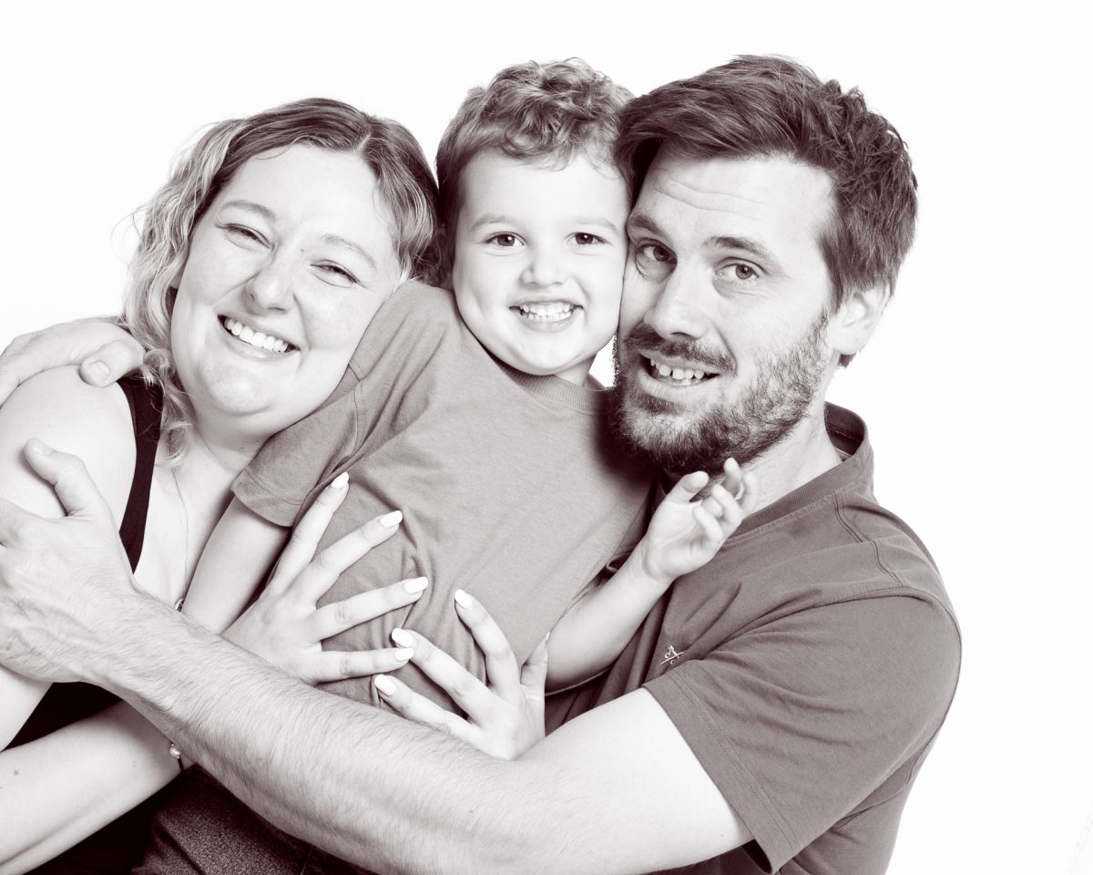 a mum dad and young son cuddle and pose for the camera