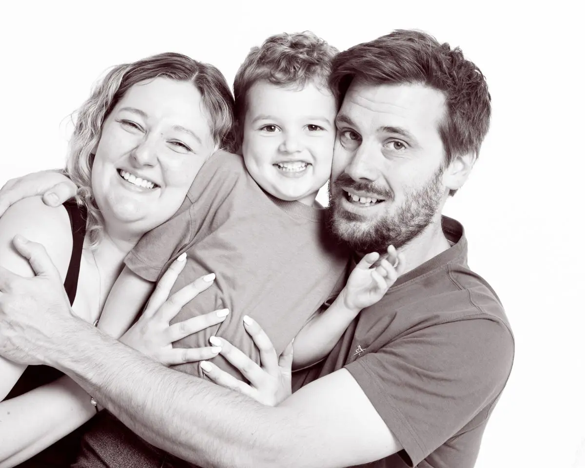a mum dad and young son cuddle and pose for the camera
