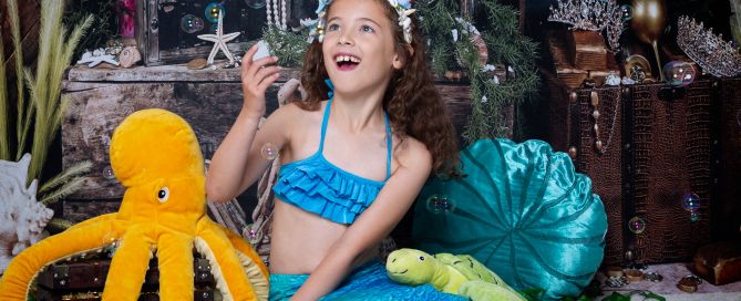 a little girl dressed as a mermaid is excited when the bubble machine is turned on