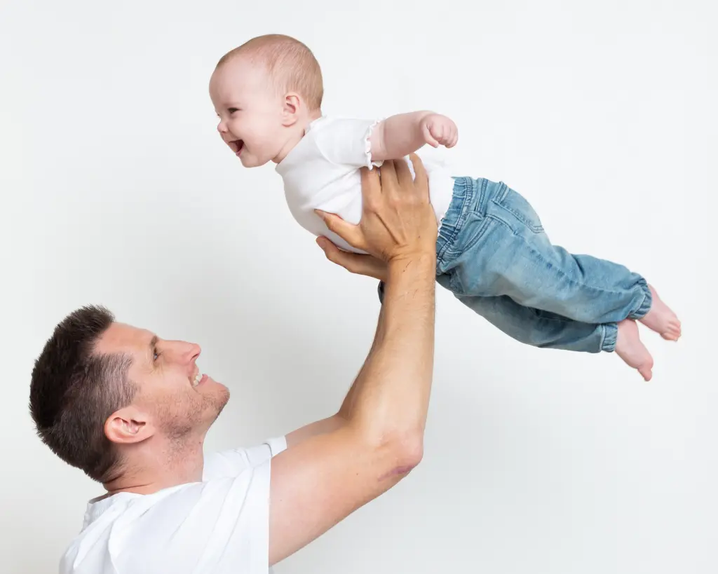 a baby is flown up in the air by their dad at a portarit session