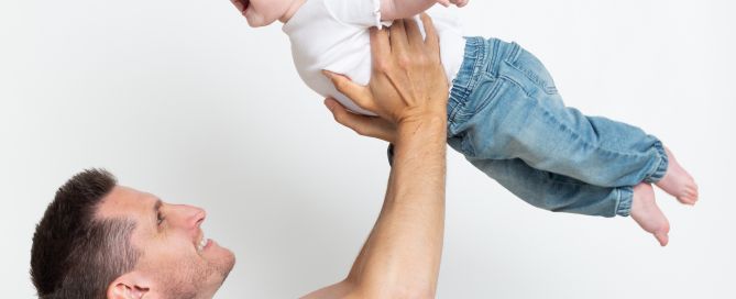 a baby is flown up in the air by their dad at a portarit session