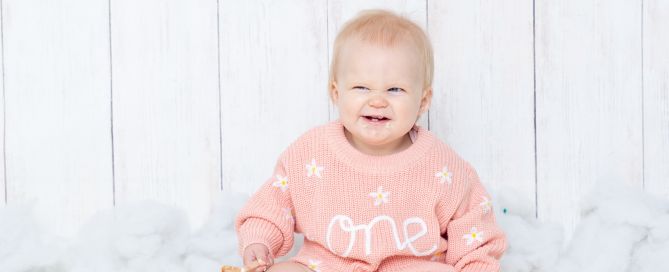 a little girl enjoys her cake at a first birthday photo shoot