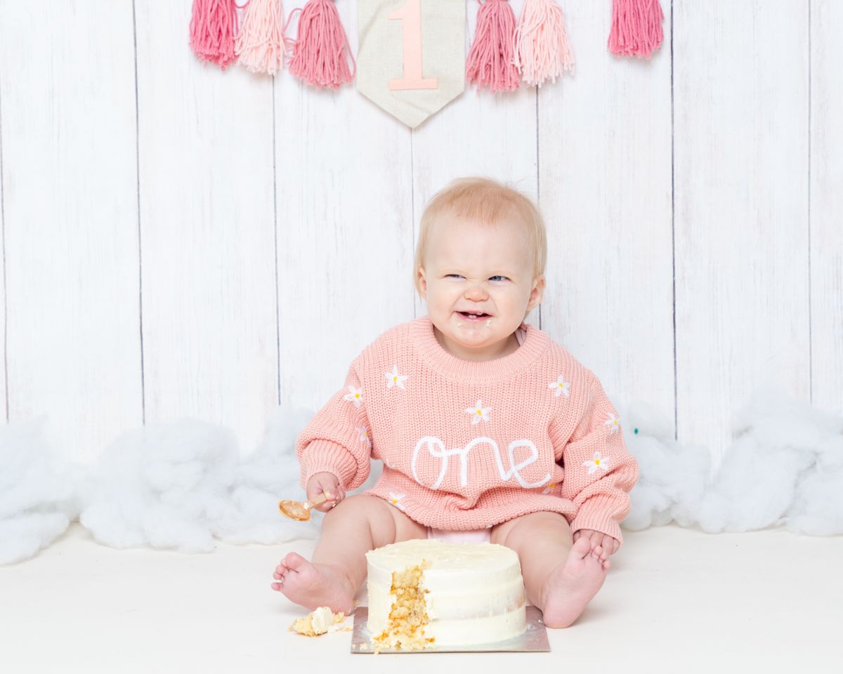 a little girl enjoys her cake at a first birthday photo shoot