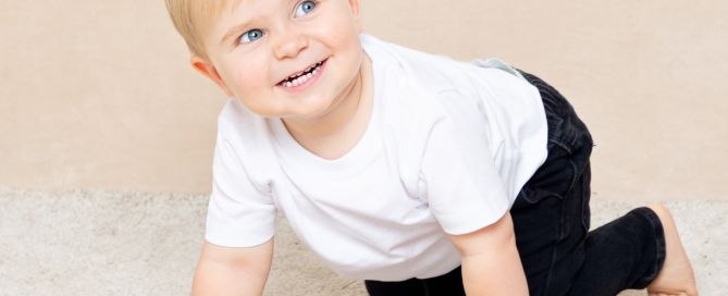 a little boy smiles as he's crawling around for a photo shoot
