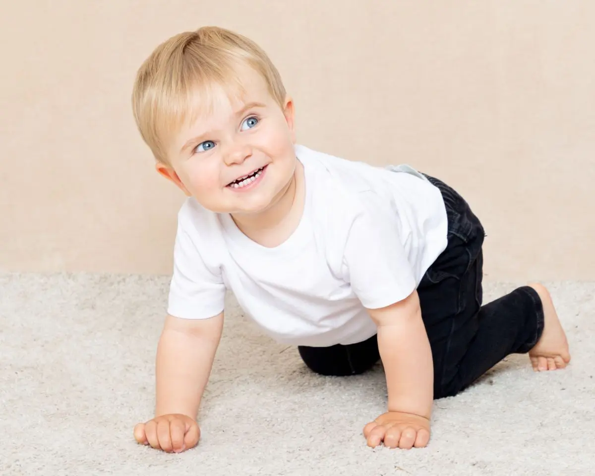a little boy smiles as he's crawling around for a photo shoot