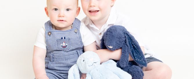 two boys pose with bunnies at a photo shoot