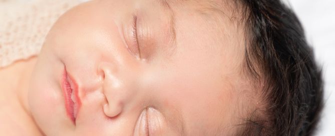 a close up of a sleeping newborn with magnificent hair