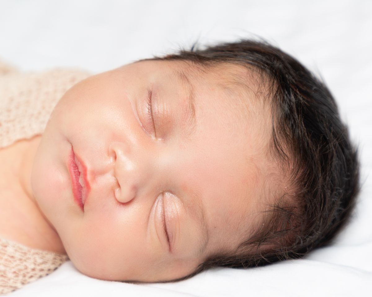 a close up of a sleeping newborn with magnificent hair