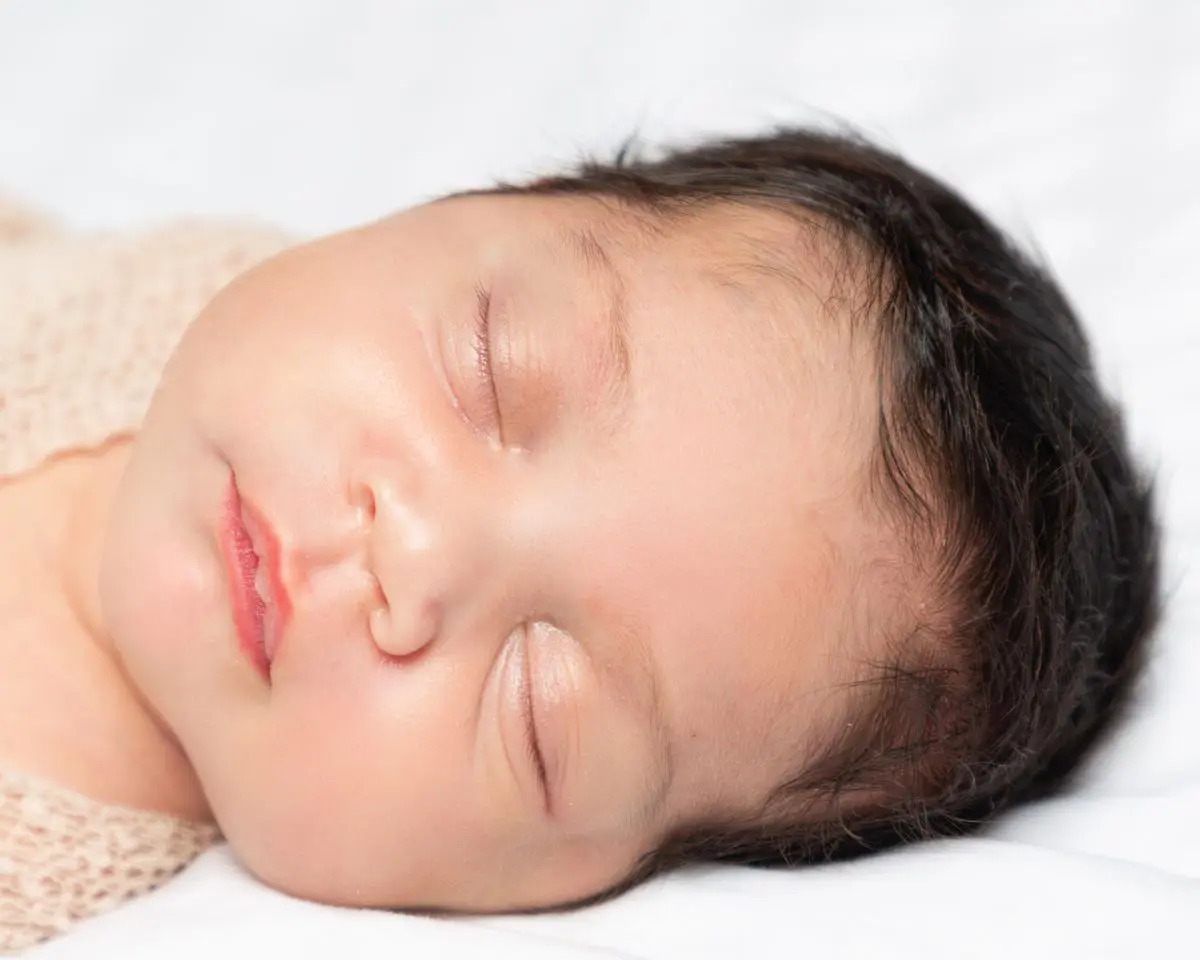 a close up of a sleeping newborn with magnificent hair