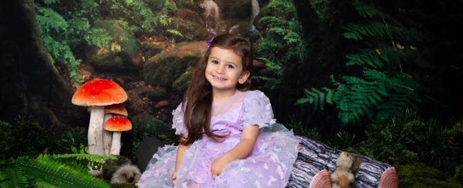 a little girl in a lilac dress in a woodland setting at a photoshoot