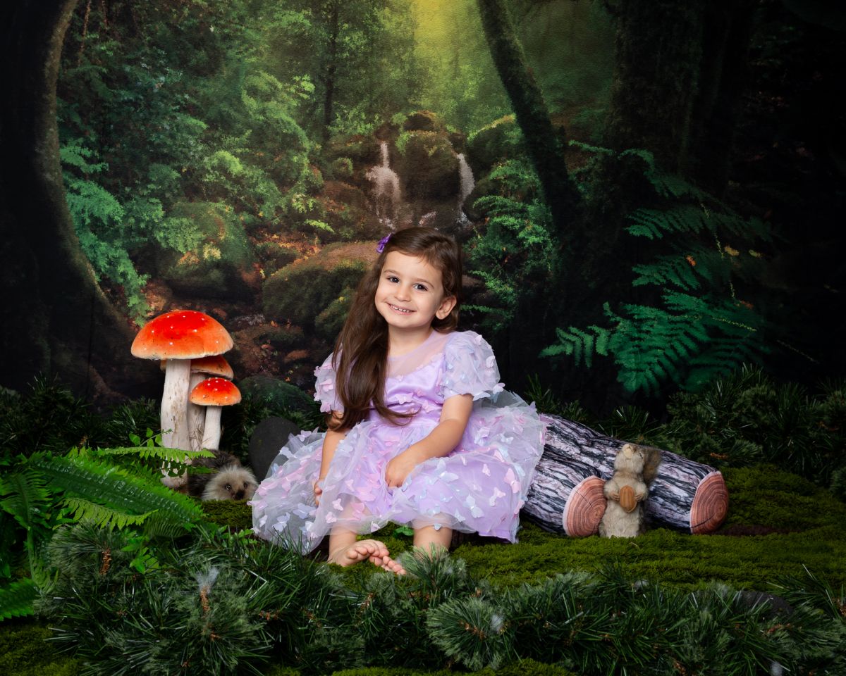 a little girl in a lilac dress in a woodland setting at a photoshoot