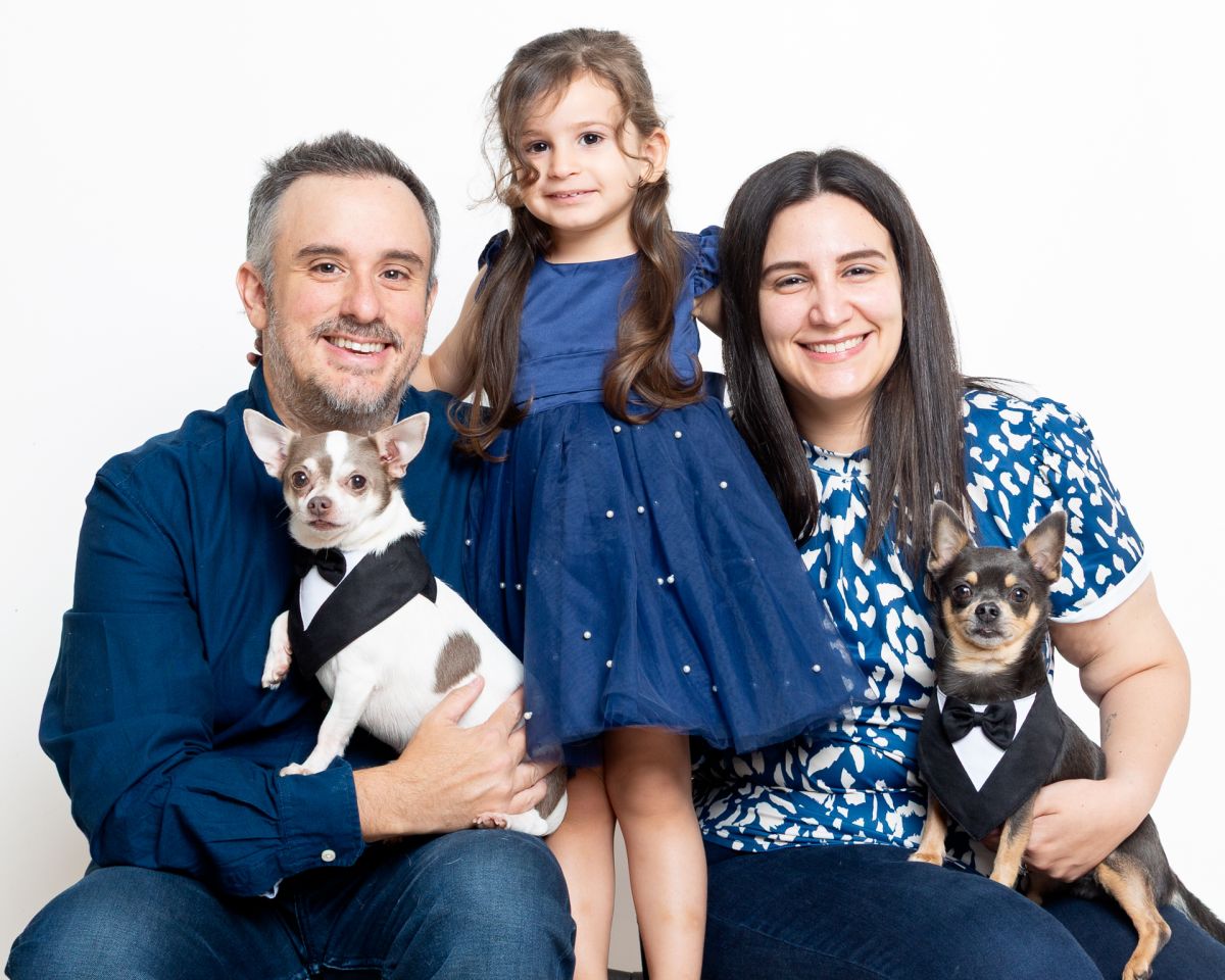a family pose together for a portrait, mum, dad, daughter and two chihuahuas