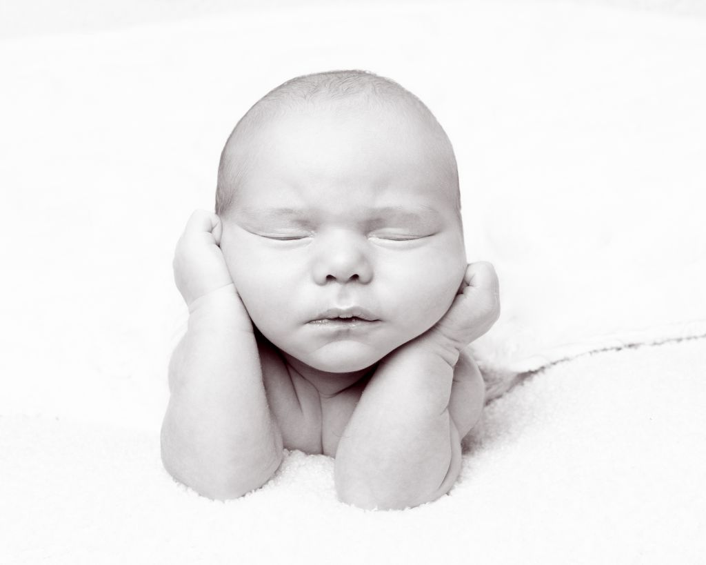 a black and white image of a newborn baby in a traditional froggy pose at a newborn photo shoot
