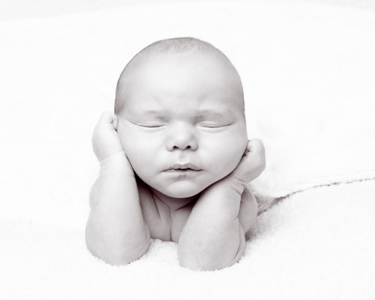 a black and white image of a newborn baby in a traditional froggy pose at a newborn photo shoot