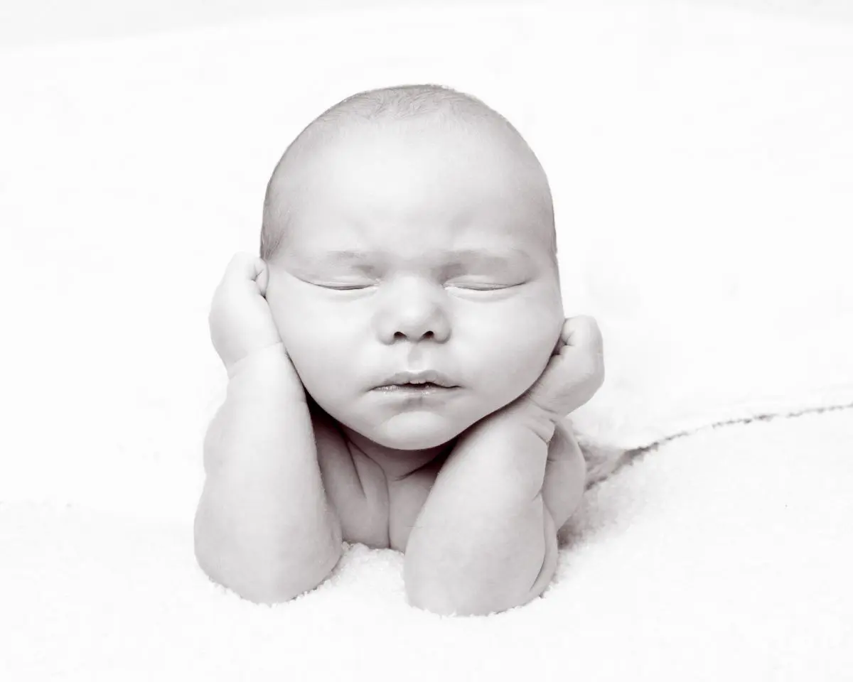 a black and white image of a newborn baby in a traditional froggy pose at a newborn photo shoot