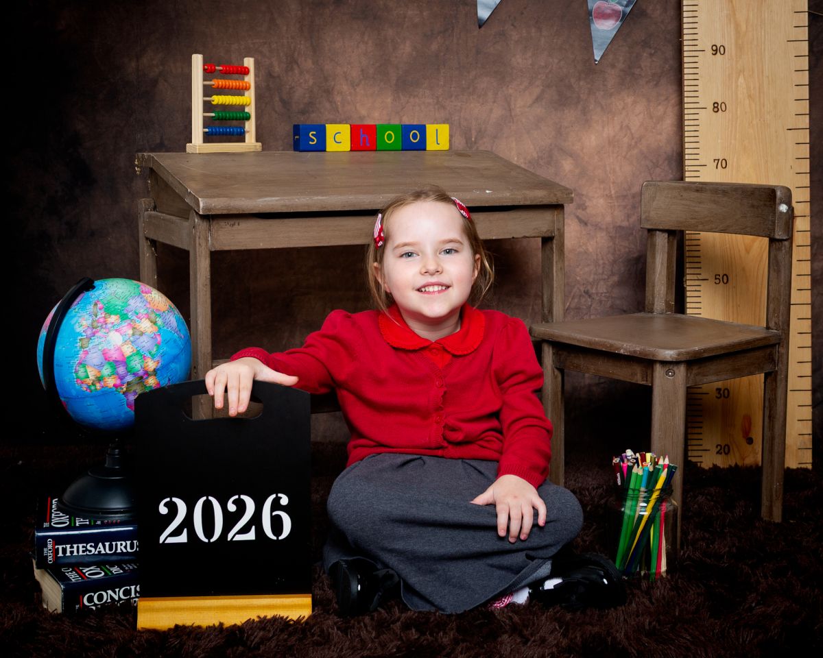 a little girl in a red school jumper at photo shoot